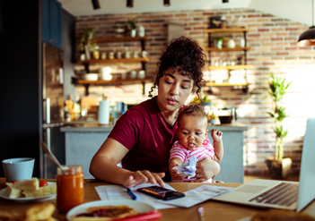 Woman working on a calculator with a baby on her lap