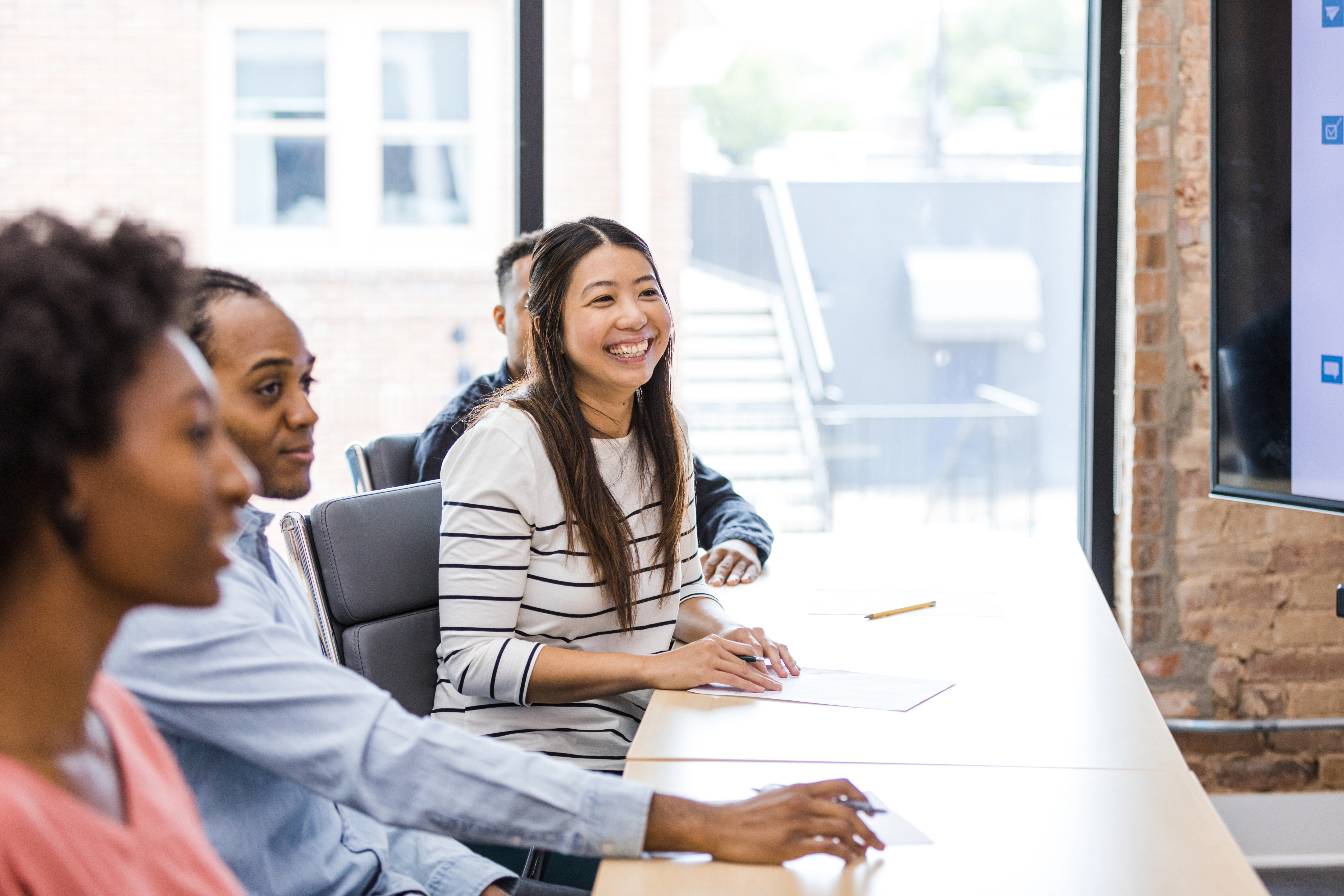 woman-working-at-desk-with-colleagues-in-meeting