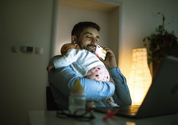 Father on the phone while he holds his baby