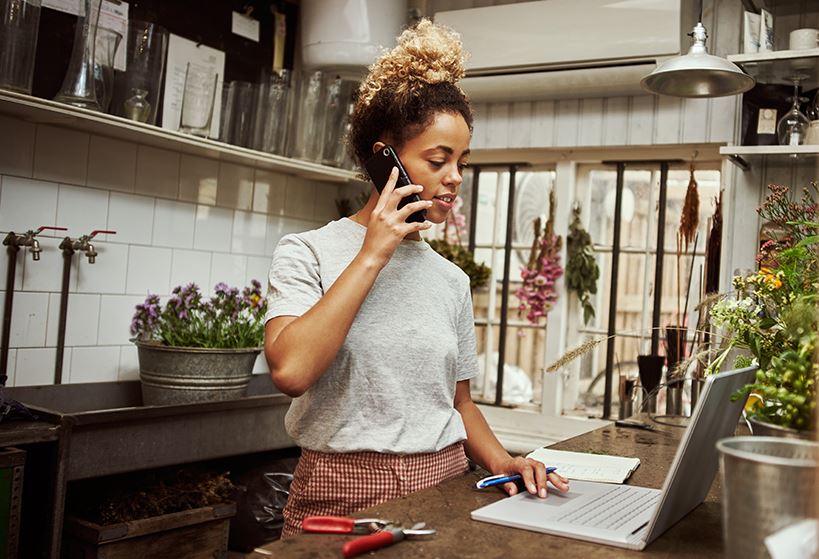 woman-talking-on-phone-in-kitchen-on-laptop