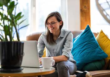 Woman sitting on a couch working on a laptop.