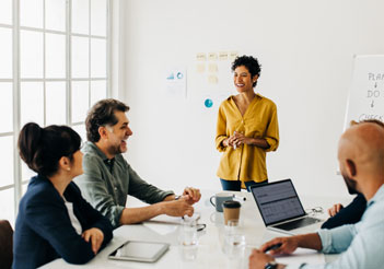 Woman in a yellow shirt leading a meeting