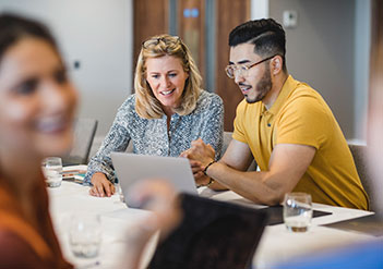 Man and woman looking at a laptop in a meeting room